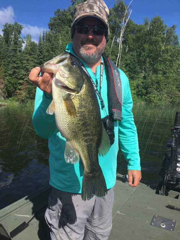 Three fishermen holding up their bass fish catches on main dock of cabin o pines on pelican lake, MN